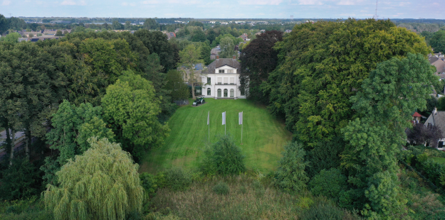 Vooraanzicht van het rijks monumentaal buitenhuis met daar omheen de groene omgeving