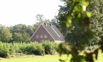 Foto van de groene omgeving met een woning in de achtergrond om