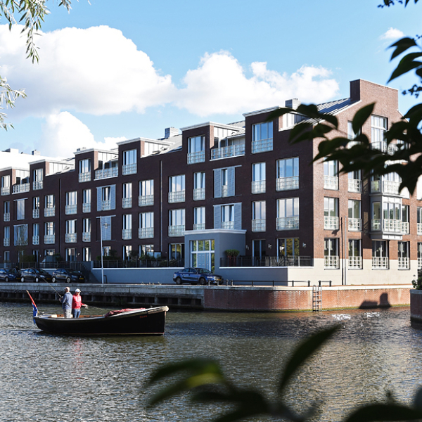 Woningen vanaf de waterkant te zien waar mensen in een bootje varen